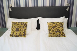 Una cama con ropa blanca y dos almohadas decorativas con estampado floral.