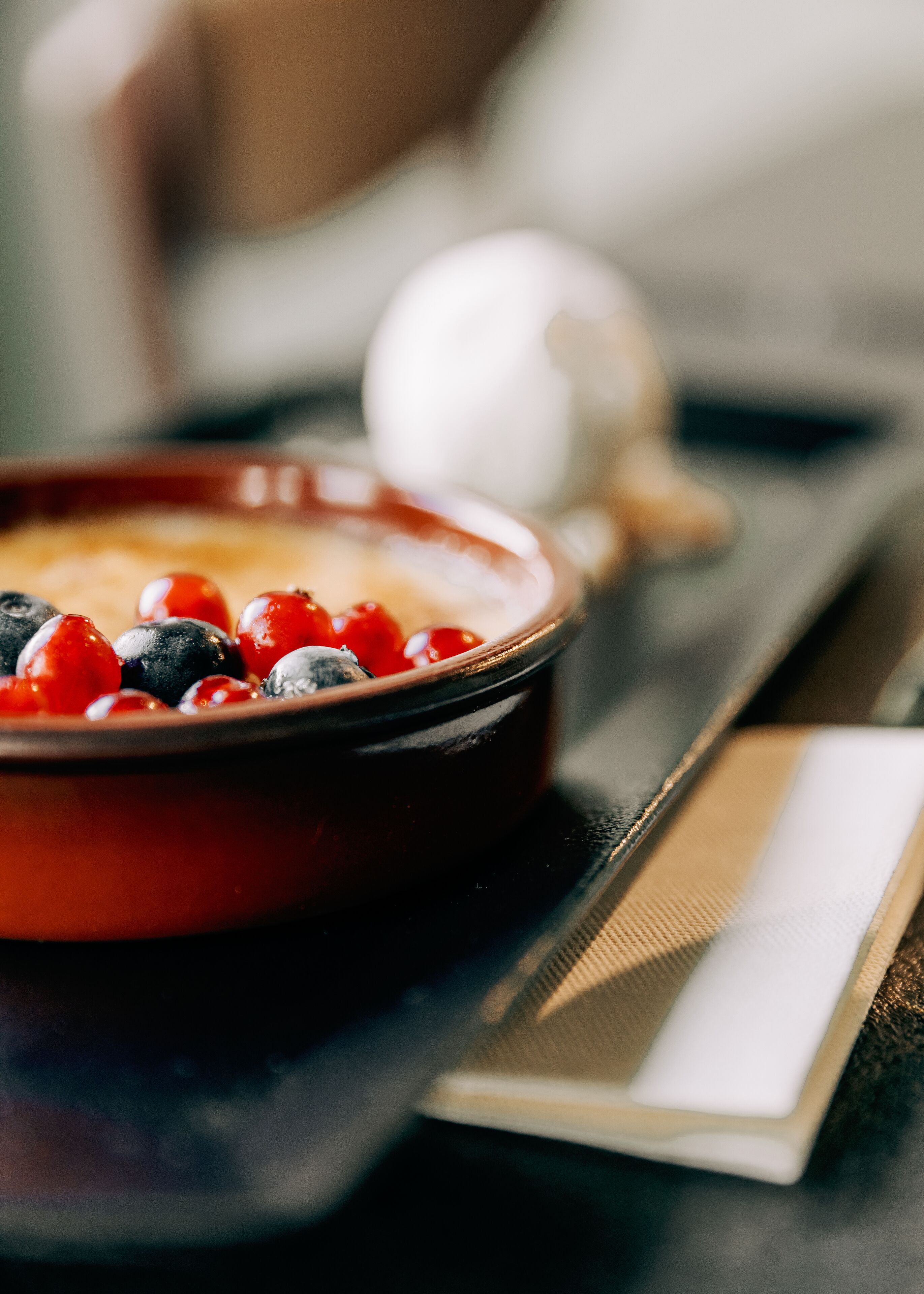 A dessert dish with berries and a scoop of ice cream on a tray.