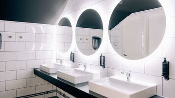 Une salle de bain moderne avec trois lavabos, chacun étant surmonté d’un miroir.