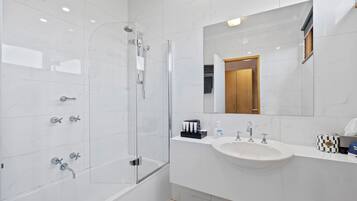Un baño moderno con ducha envuelta en vidrio, un lavabo blanco y un espejo sobre el lavabo.