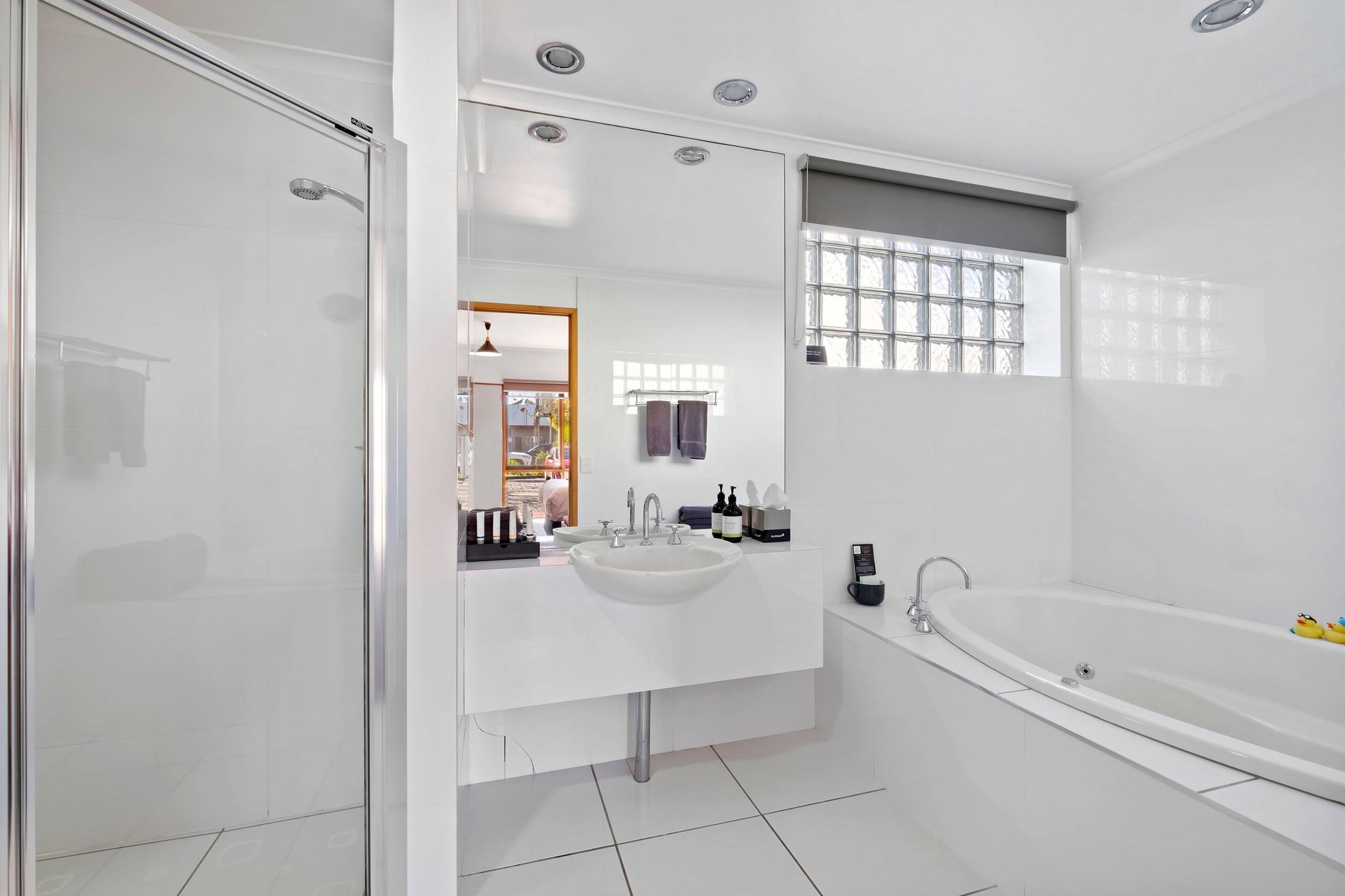 A modern bathroom with a glass shower enclosure, a freestanding bathtub, and a vanity with a sink and mirror.