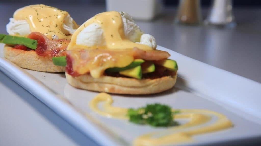 Un plato de desayuno con huevos, aguacate y tocino.