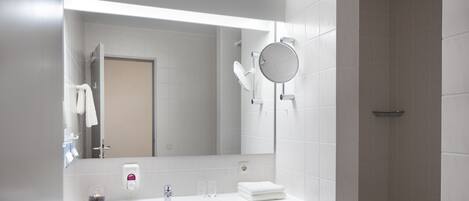 A modern bathroom with a white sink, mirror, and towel rack.