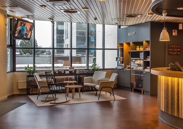 A modern interior with a reception desk, seating area, and large windows offering a view of the outside.