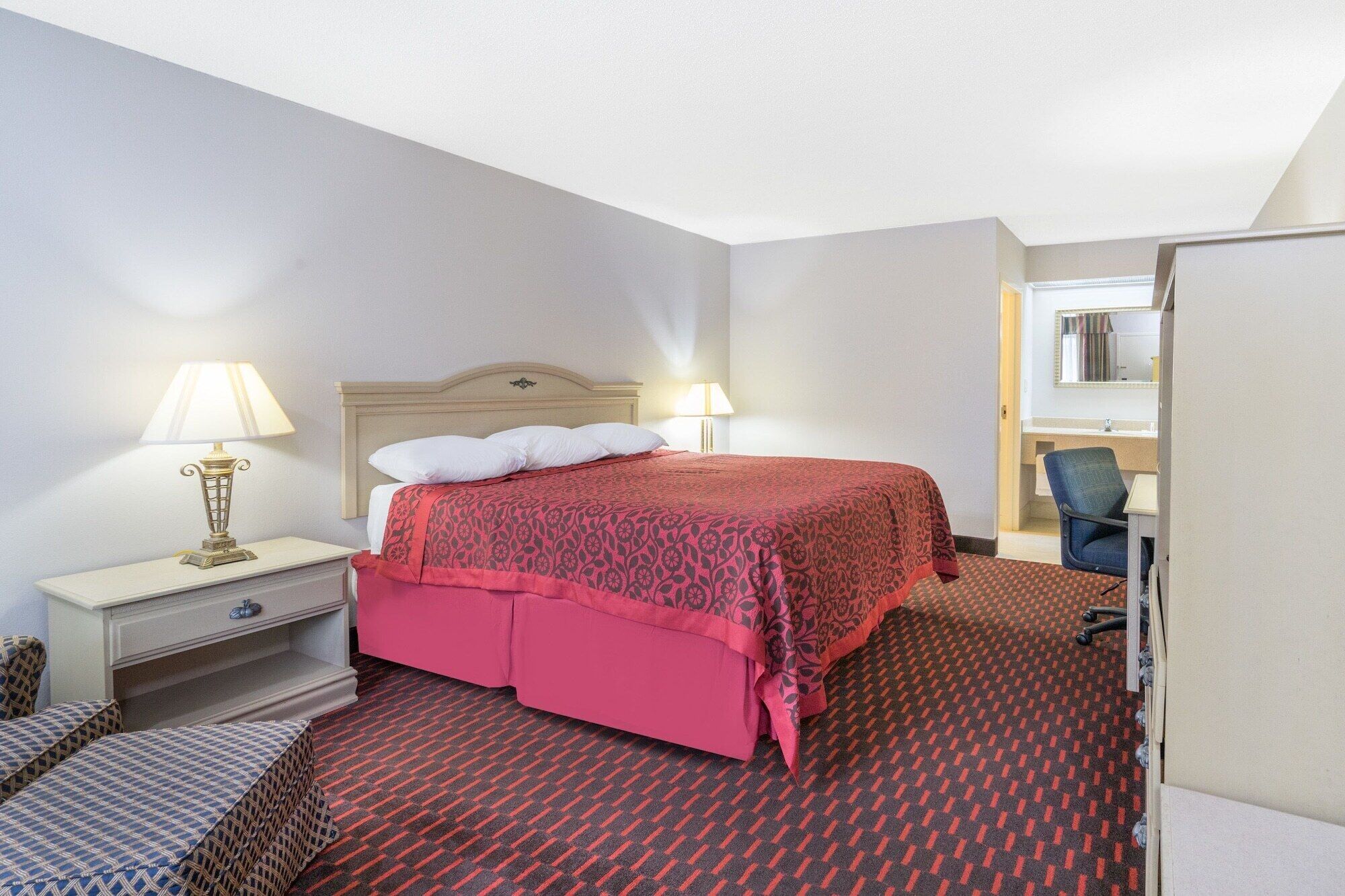Habitació d'hotel amb un llit, dues làmpades de nit, un escriptori amb una cadira i un mirall.