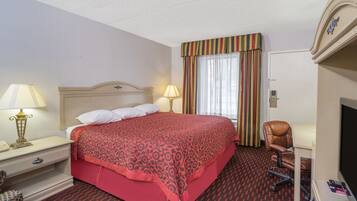 Una habitación de hotel con una cama, dos lámparas de noche, una silla, un televisor y una puerta.