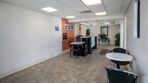 A hallway with a reception desk, chairs, and a small table. - Motel 6 London, KY (London)