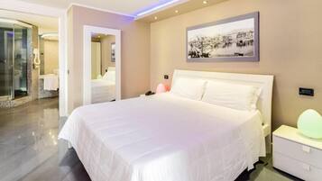 A modern hotel room with a large bed, a bedside table, a nightstand, and a wall-mounted picture.