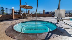 Une piscine de forme circulaire, entourée d’une terrasse en pierre et d’une clôture en métal.