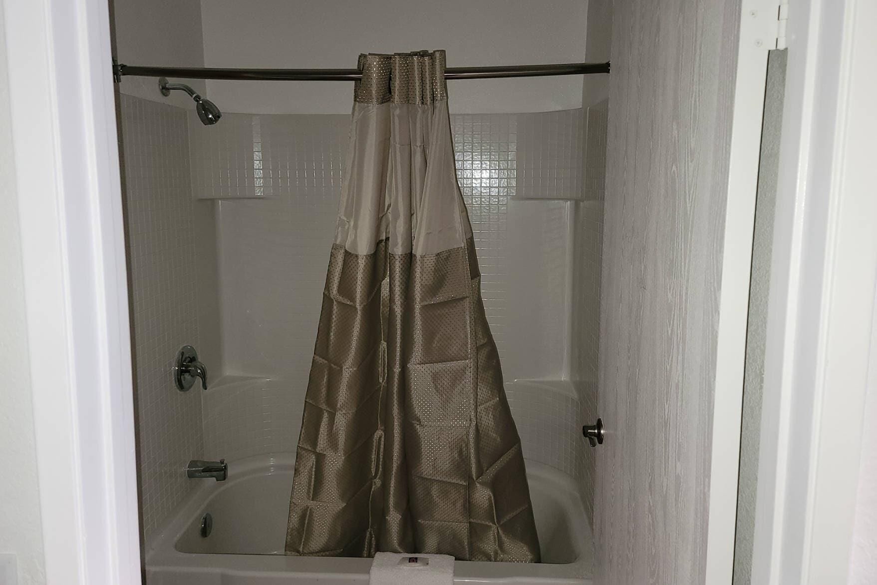 A bathroom with a shower curtain, a bathtub, and a toilet.