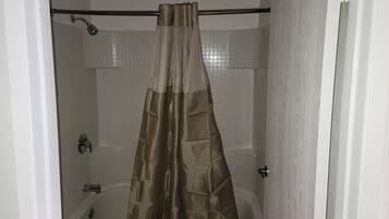 A bathroom with a shower curtain, a bathtub, and a toilet.
