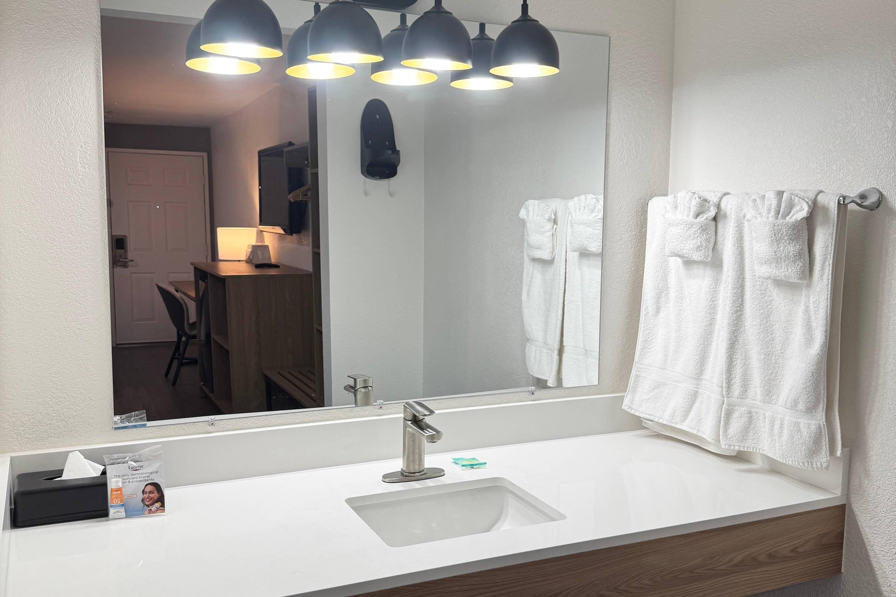 A bathroom with a white sink, a mirror, and a towel rack with towels.