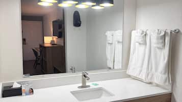 A bathroom with a white sink, a mirror, and a towel rack with towels.