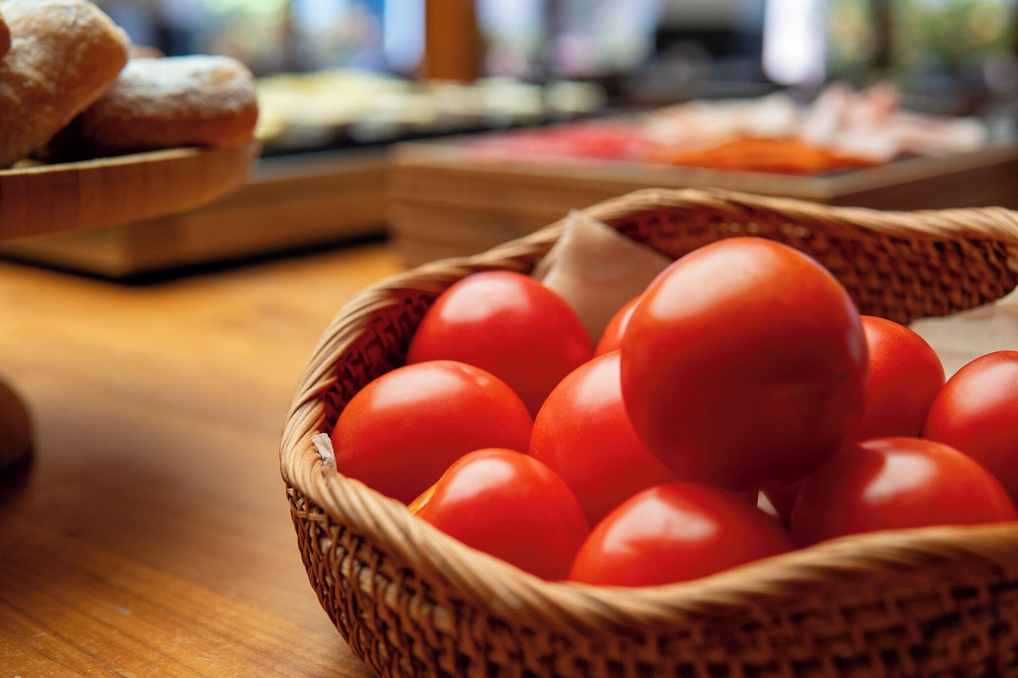 A basket of tomatoes on a wooden table.