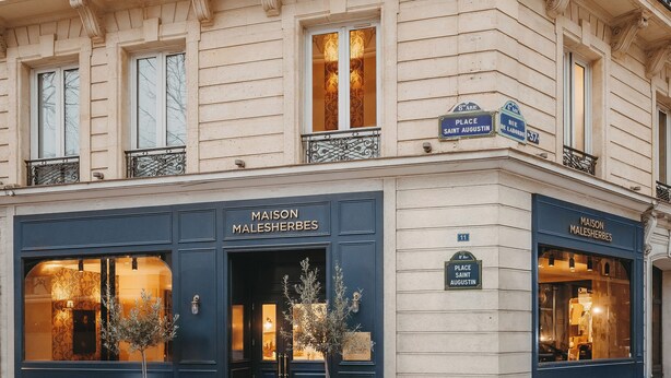 Ein Gebäude mit blauer Fassade, zwei Eingänge mit der Aufschrift "MAISON MALESHERBES" und ein schmiedeeiserner Balkon.