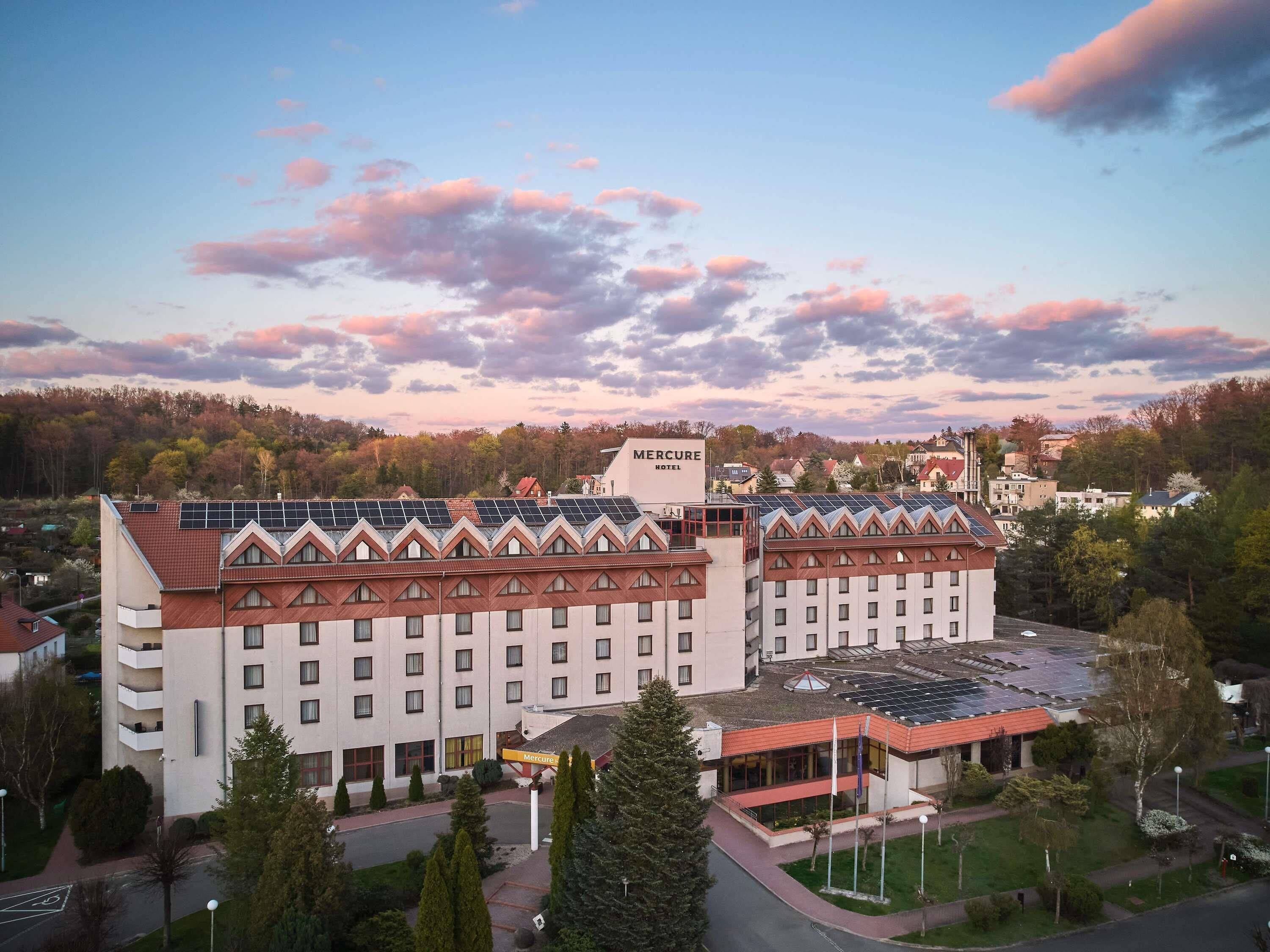 Un hotel de varios pisos, con un letrero llamativo y paneles solares en el techo.