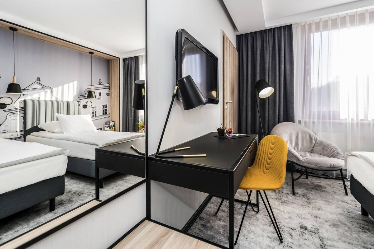 Ein modernes Hotelzimmer mit Bett, Schreibtisch und Sitzgelegenheit.
