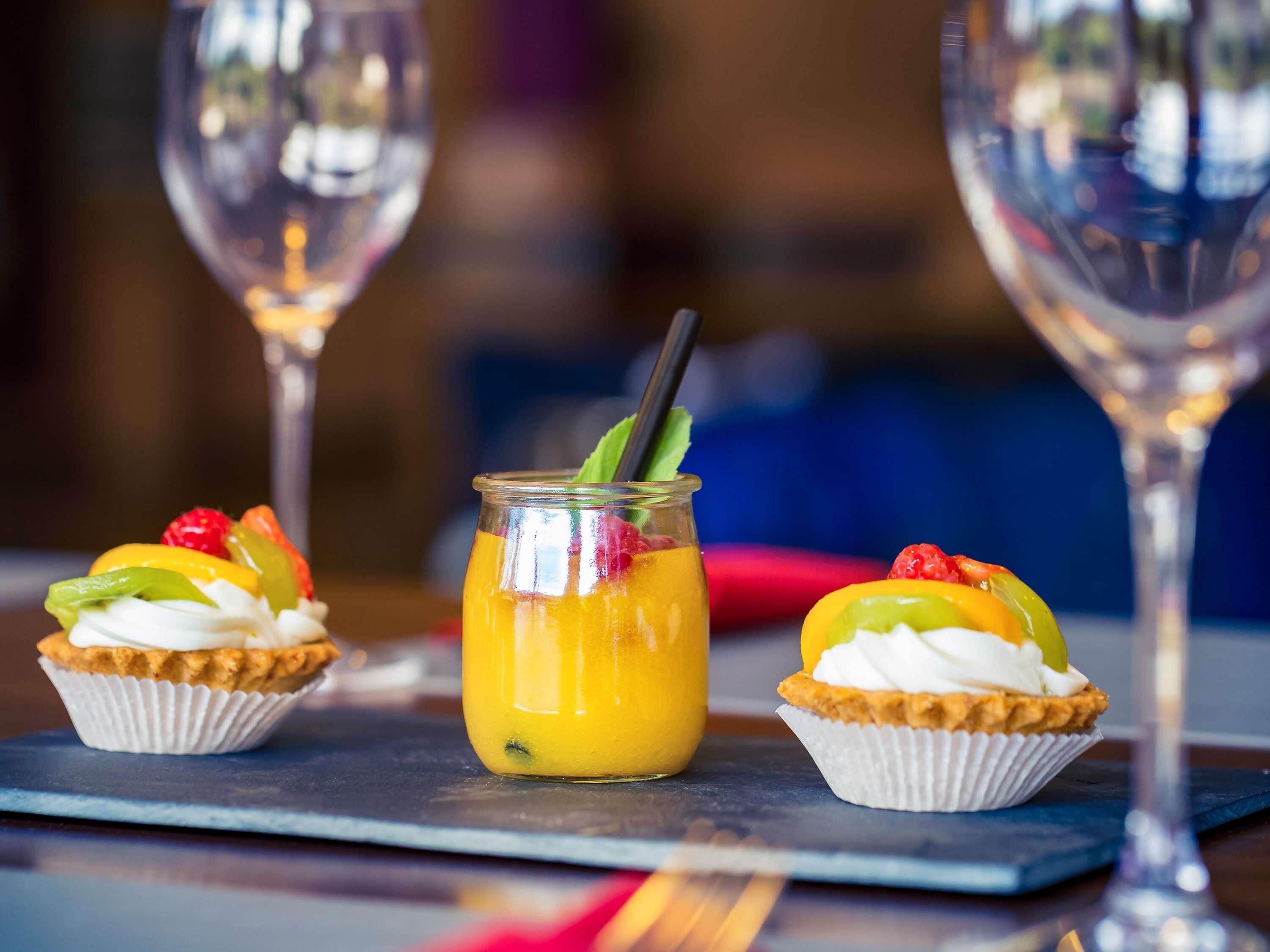 Una presentación de postres que incluye dos cupcakes y una bebida de frutas sobre una tabla de pizarra.