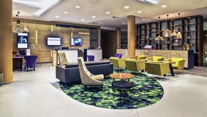 A modern lobby with a reception desk, seating area, and a bar.