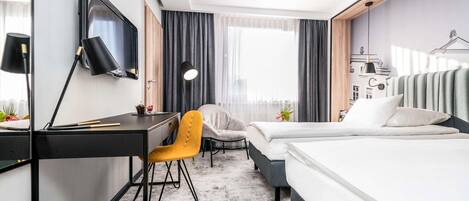 Una habitación de hotel con cama, escritorio, silla y televisor instalado en la pared.