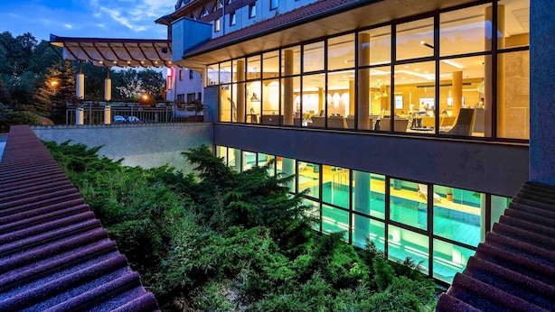 A modern building with large windows, a swimming pool, and a covered outdoor area.