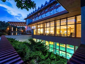 Ein modernes Gebäude mit großen Fenstern, einem Schwimmbad und einem überdachten Außenbereich.