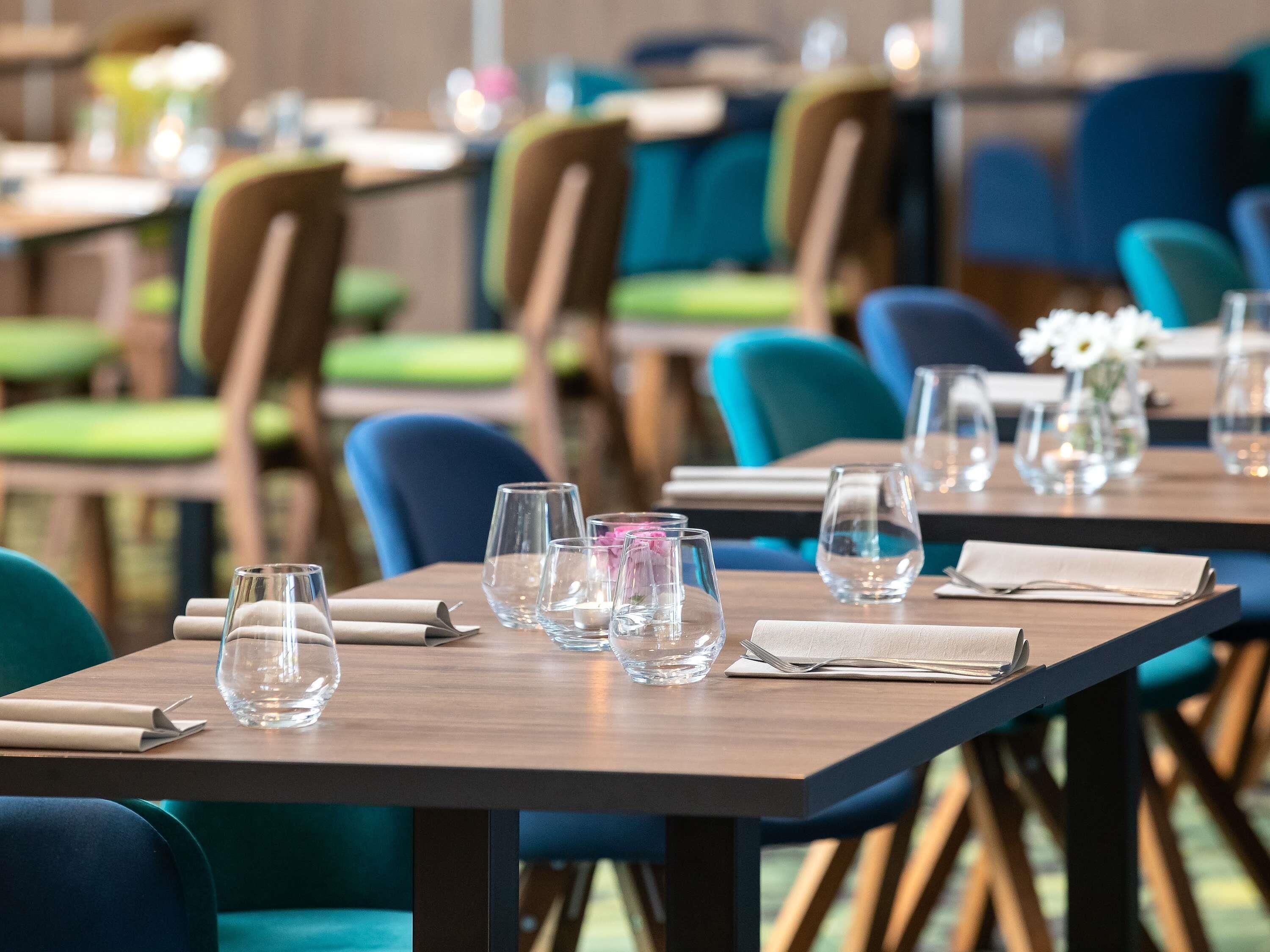 A restaurant with tables set for dining, chairs, and clear glassware.