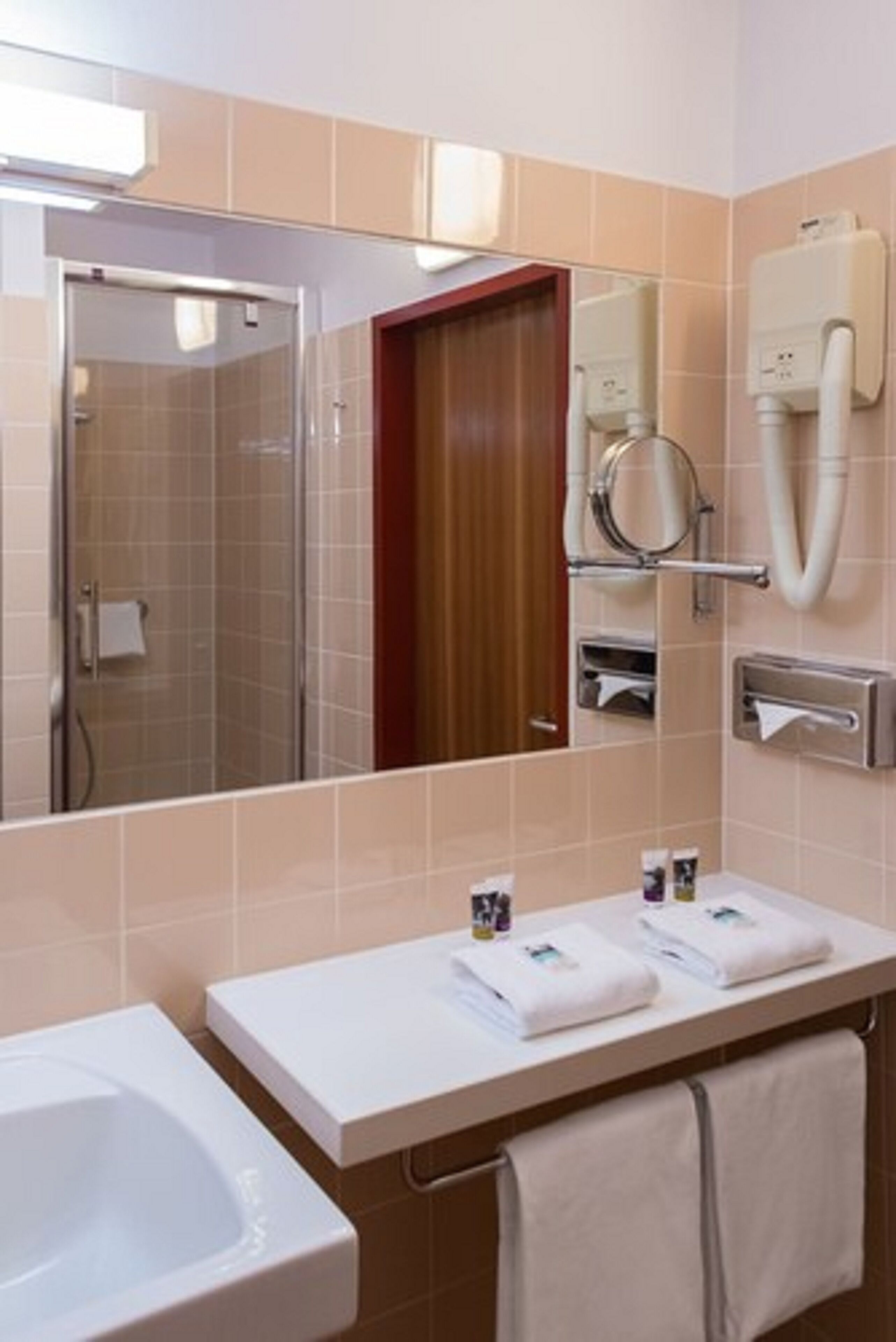 A bathroom with a sink, mirror, towel rack, and a shower stall.