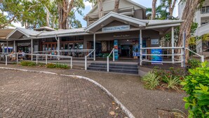 A building with a covered entrance, outdoor seating area, and a sign reading "Paradise Cove Beach". - Paradise on the Beach Resort - Palm Cove (Palm Cove)