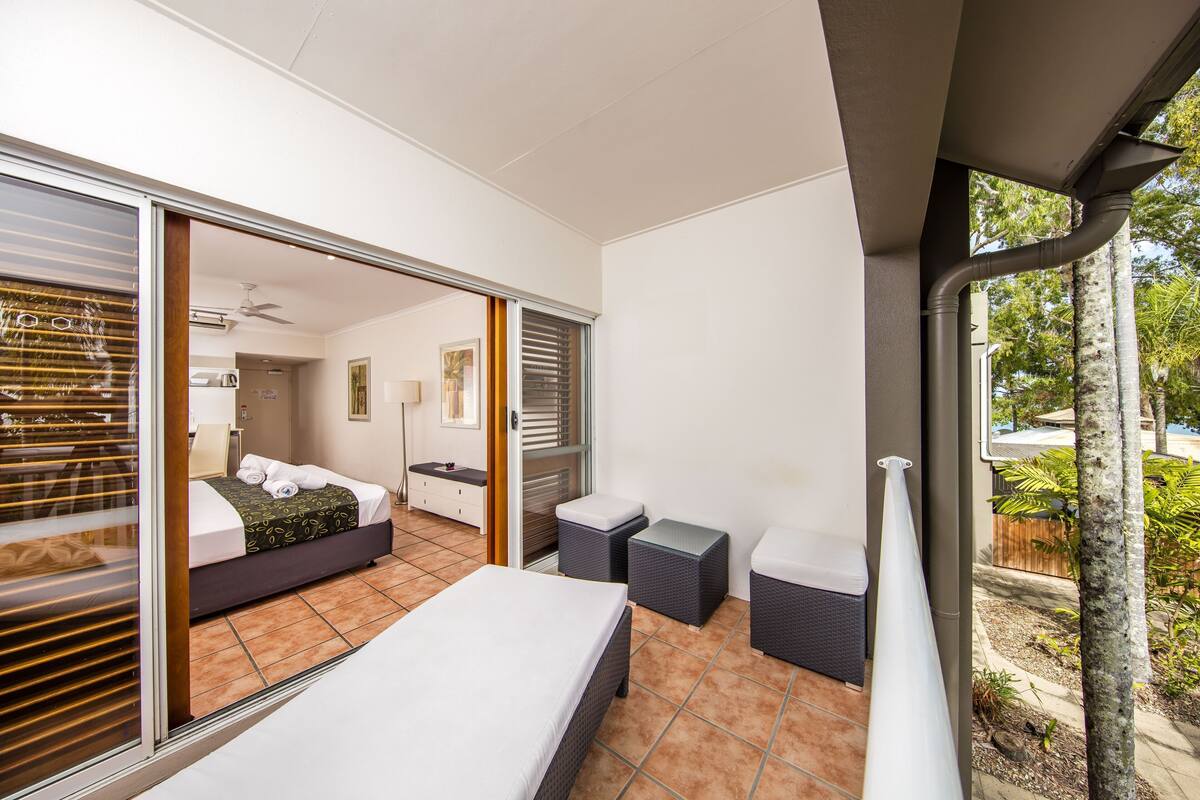 Ein Schlafzimmer mit einem Bett, einer Glasschiebetür, einem kleinen Tisch und einem Stuhl.