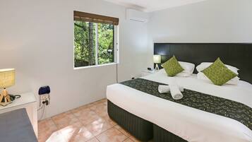 Habitación de hotel con una cama grande, un escritorio, una ventana con persianas y aire acondicionado instalado en la pared.
