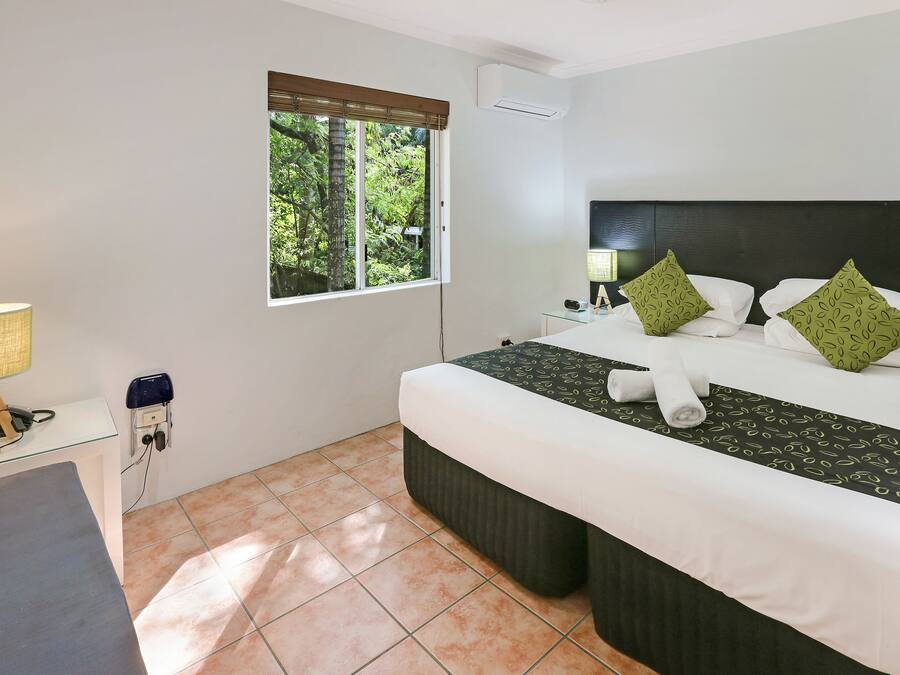 Habitación de hotel con una cama grande, un escritorio, una ventana con persianas y aire acondicionado instalado en la pared.