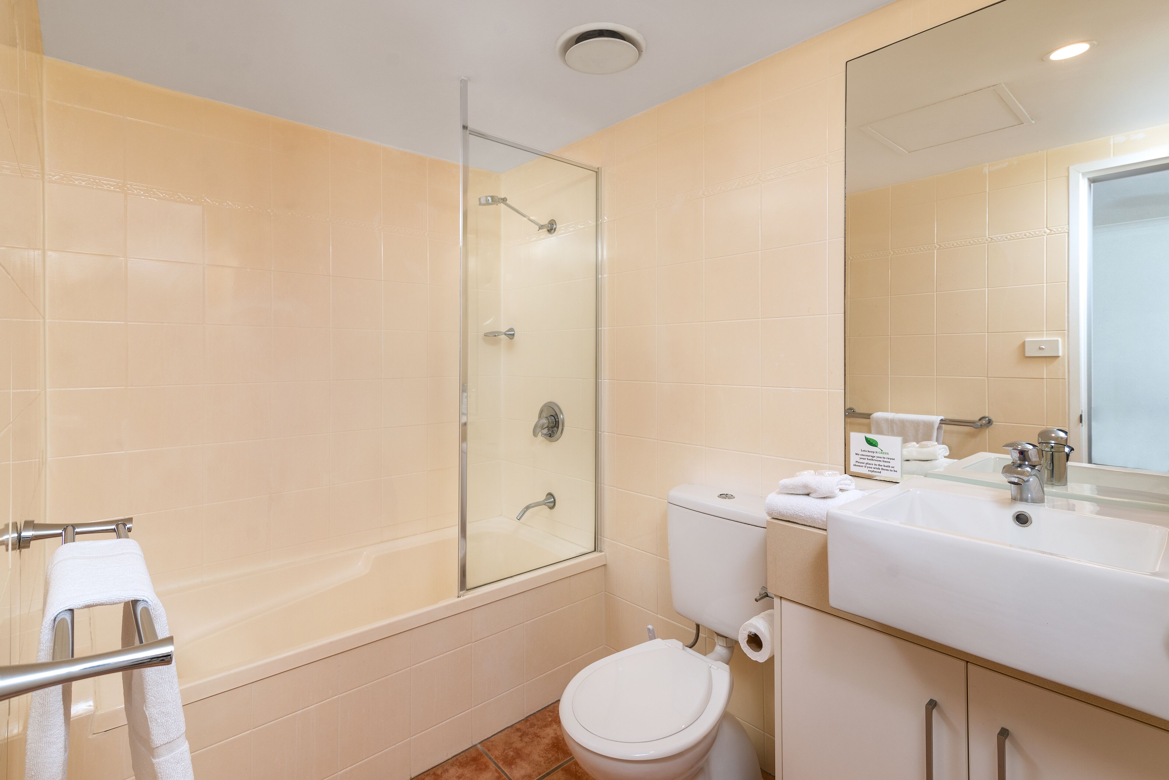 Un baño con ducha de vidrio, inodoro, lavamanos y espejo.