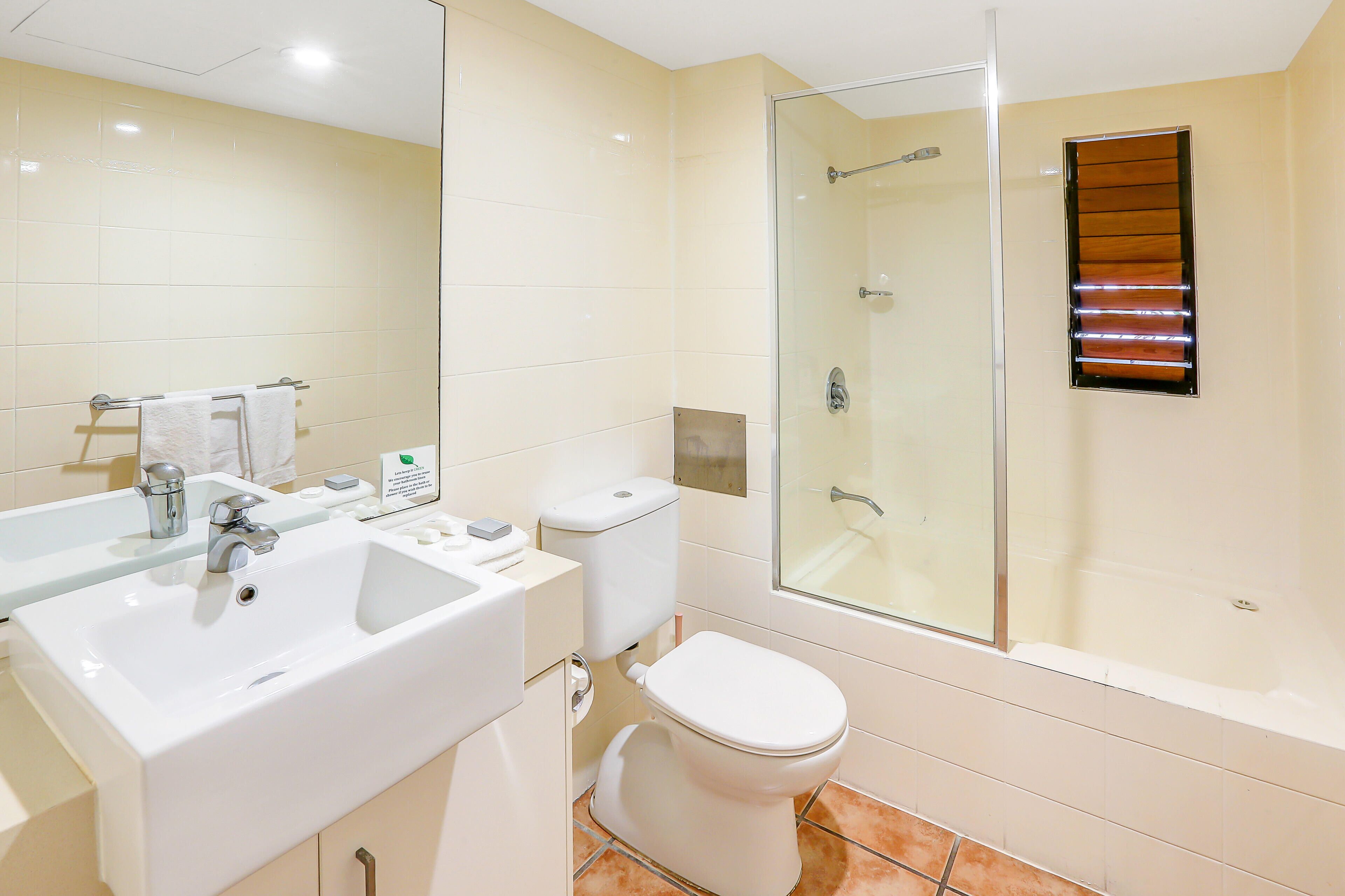 A modern bathroom with a white sink, mirror, toilet, and glass shower enclosure.
