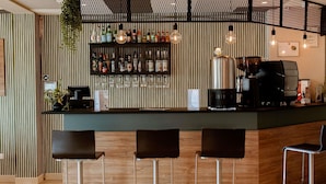 Un espace bar avec un comptoir en bois, des tabourets de bar et une variété de bouteilles et de verres.