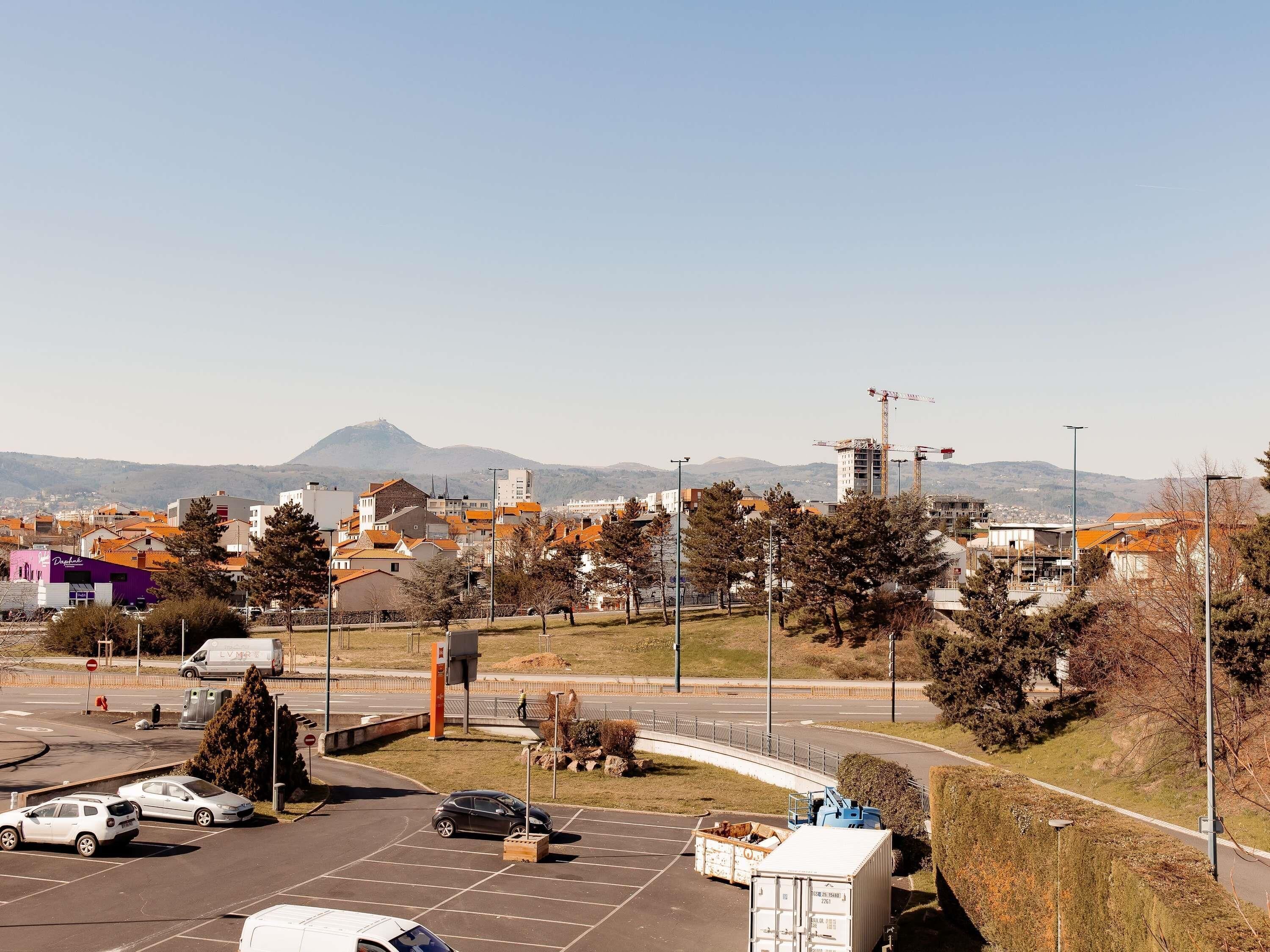 A parking lot with cars, a construction site, and buildings in the background.