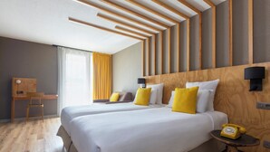 A hotel room with two beds, a desk, and a telephone.