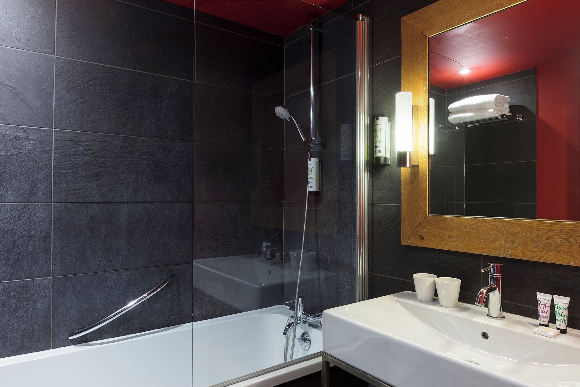A modern bathroom with a glass-enclosed shower, a white bathtub, and a large mirror.