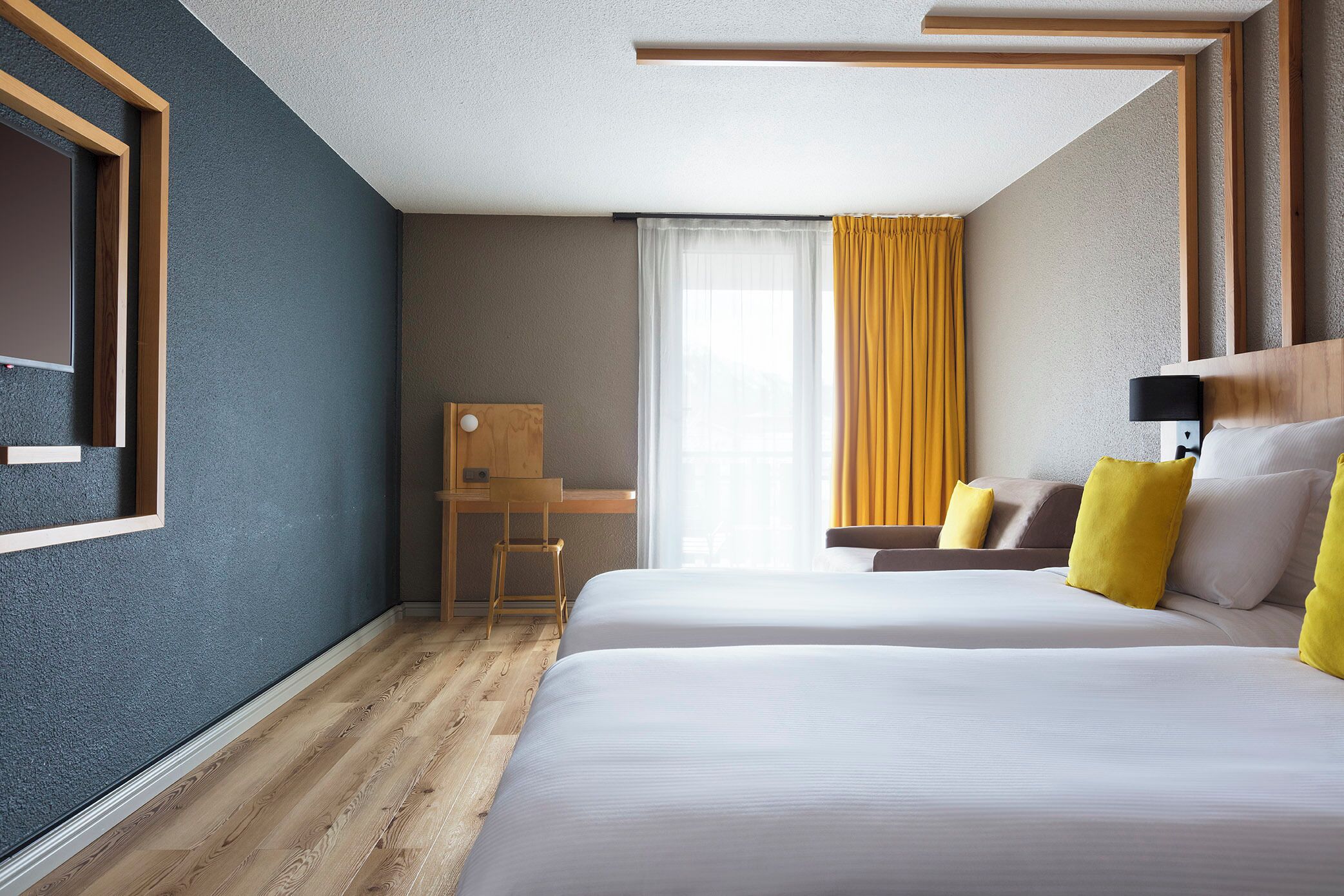 Een hotelkamer met twee bedden, een bureau en een stoel.