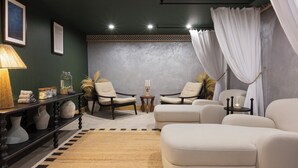 A cozy living room with a sofa, two armchairs, a small side table, and a lamp.