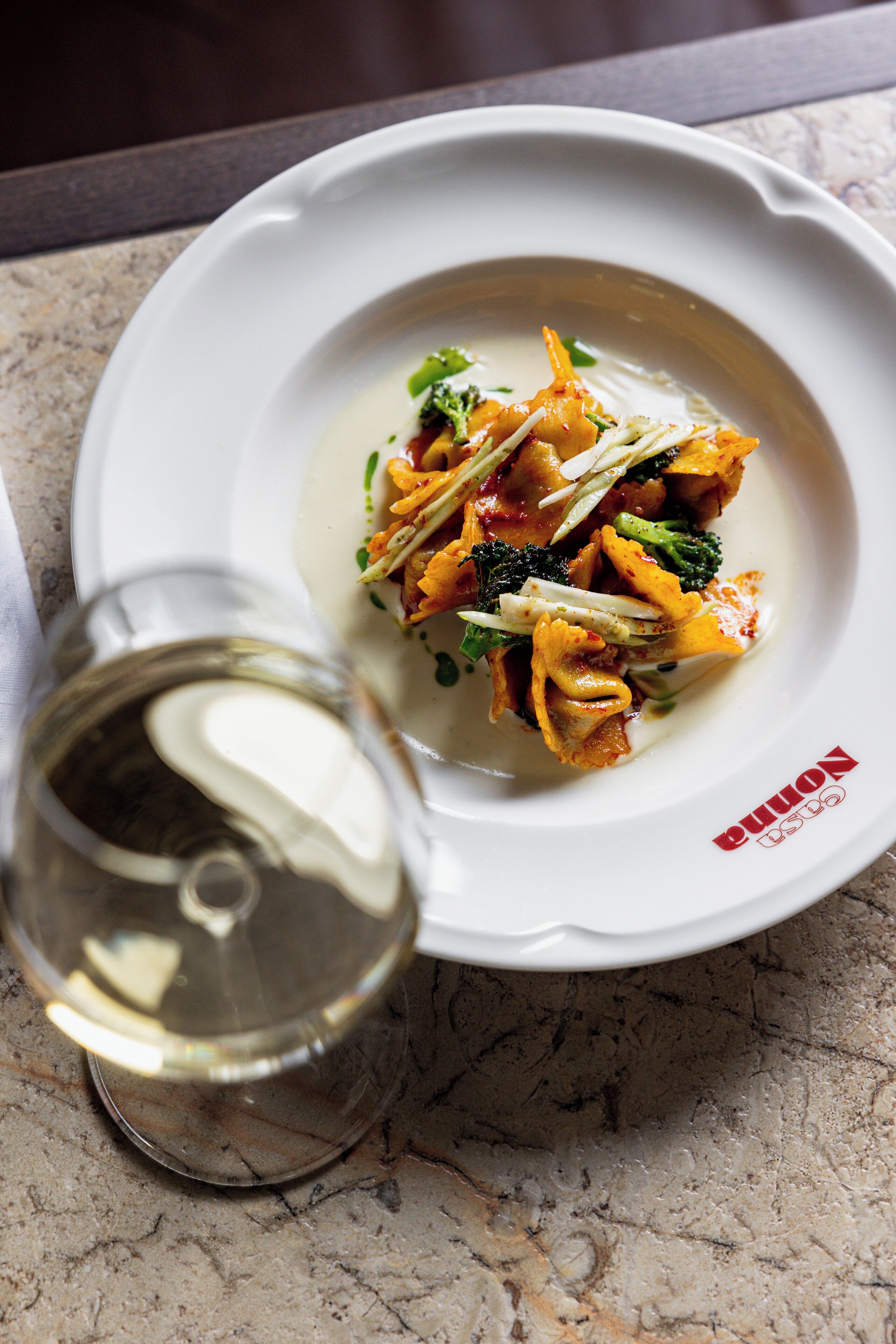 A white plate with a dish of food and a glass of water on a marble surface.