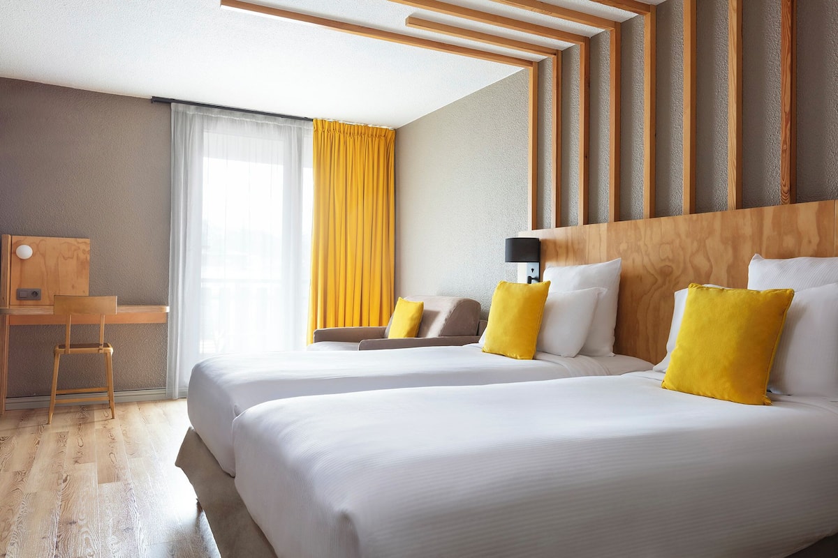 Een hotelkamer met twee bedden, een bureau en een stoel.