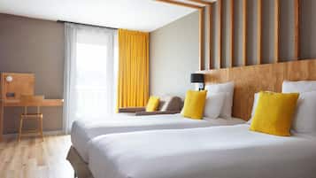 A hotel room with two beds, a desk, and a chair.