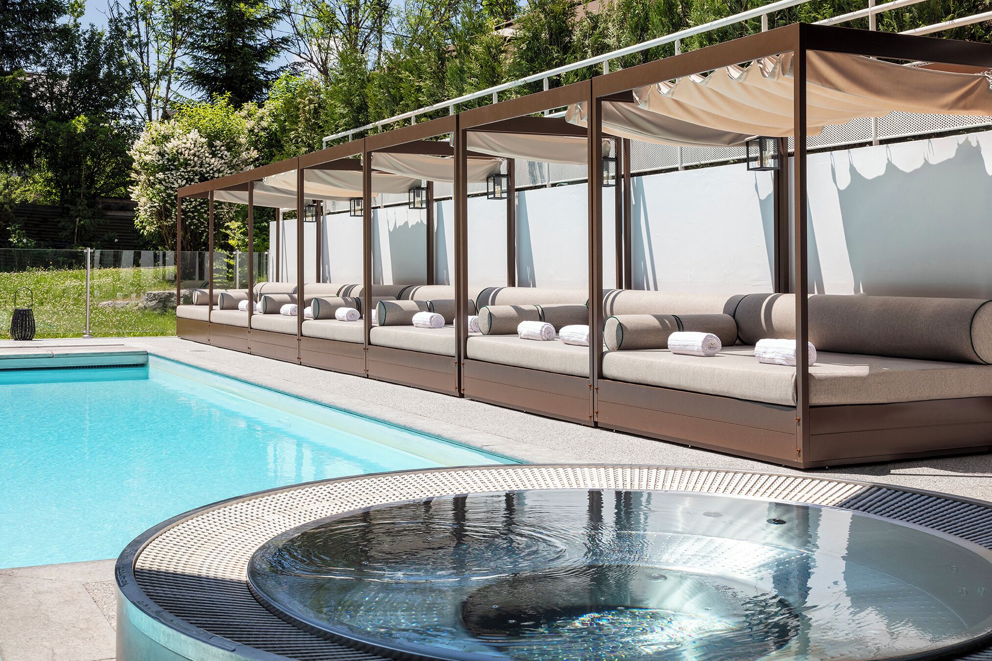 A poolside area with a hot tub, lounge chairs, and a covered seating area.