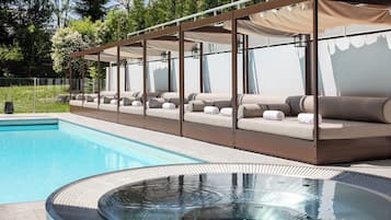 A poolside area with a hot tub, lounge chairs, and a covered seating area.