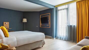 Ein Hotelzimmer mit zwei Betten, einem Nachttisch aus Holz, einer Lampe und einem an der Wand montierten Fernseher.
