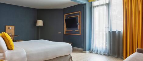 Ein Hotelzimmer mit zwei Betten, einem Nachttisch aus Holz, einer Lampe und einem an der Wand montierten Fernseher.