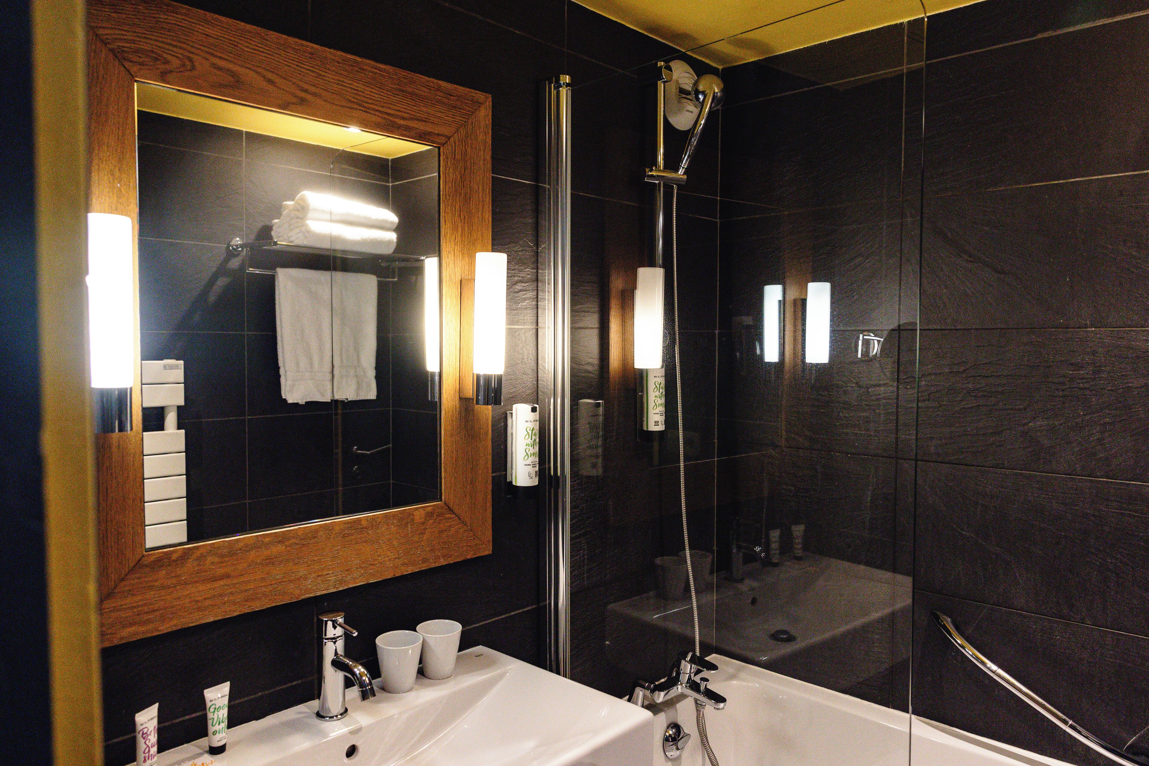 Un bany modern amb un mirall gran, una banyera, una dutxa i un lavabo.