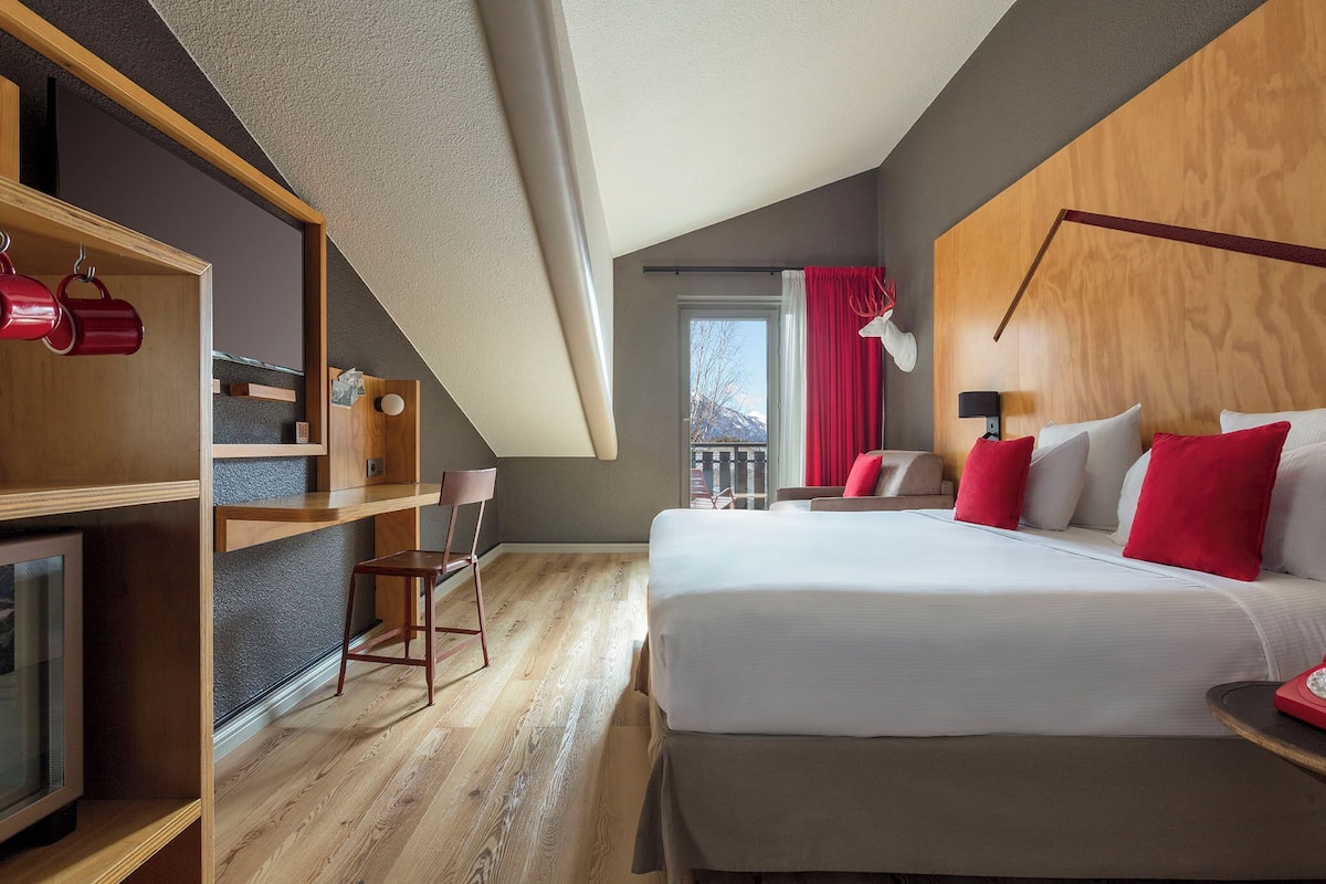 Een moderne hotelkamer met een groot bed, een bureau en een televisie.
