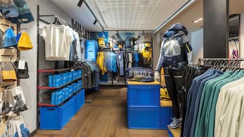 A clothing store with racks of clothes, a mannequin, and blue storage bins.